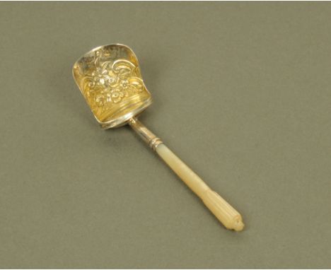 A George III silver shovel form caddy spoon, with carved mother of pearl terminal, the silver gilt bowl embossed with flowers