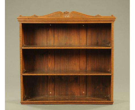 An oak and pine three tier wall mounted bookcase, with shaped and carved crest rail and incised edge decoration.  CONDITION R