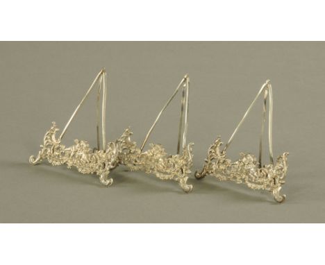 A set of three easel form late Victorian silver menu holders, by M. &amp; Co., pierced and embossed with cupids and flowers. 