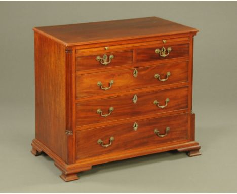 A George III mahogany chest of drawers, with moulded edge above a slide and two short and three long graduated drawers with b