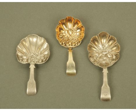 A George III silver gilt fiddle pattern caddy spoon, by Samuel Pemberton, with floral embossed bowl and two similar spoons al