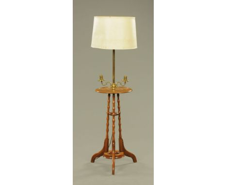An early 20th century brass and mahogany lamp standard, with twin scrolled brass sconces over a circular dished top and turne