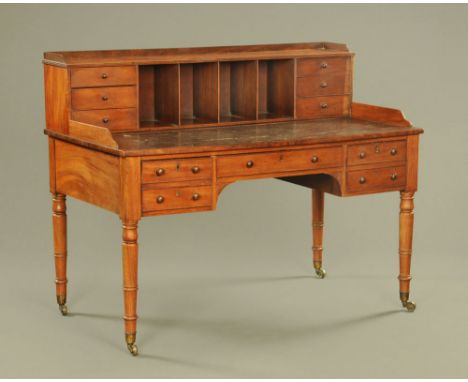 A late Georgian mahogany desk, with stage back fitted with drawers and pigeonholes with leatherette writing surface above a s