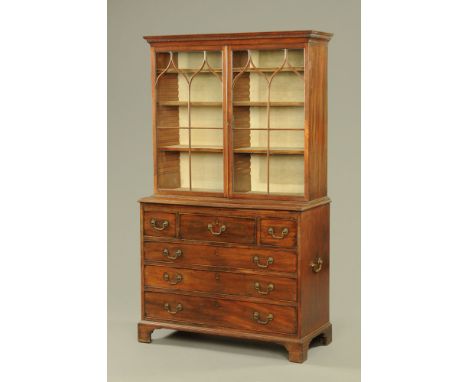 A George III mahogany glazed cupboard on chest, with dentil cornice above a pair of glazed doors enclosing adjustable shelves