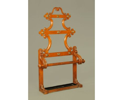 A Victorian oak coat and umbrella stand, the shaped back fitted with seven brass hooks above a cylindrical rail supported by 