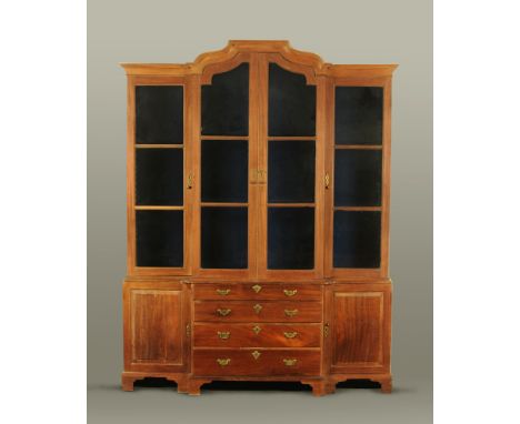 A figured mahogany breakfront bookcase of Georgian style having a central arched crest above triple glazed panelled doors and