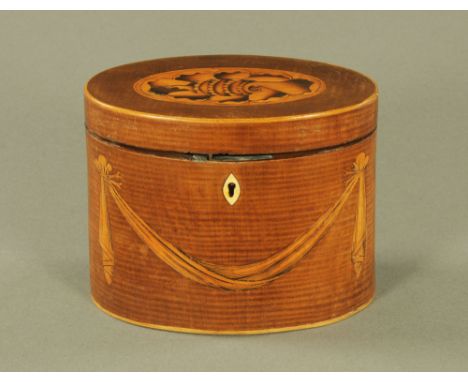 A George III figured mahogany oval tea caddy, inlaid to lid with shell paterae and to front with swag motif.  11.5 cm high.