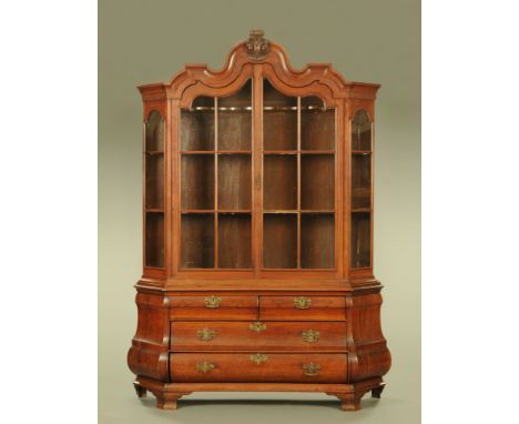 A 19th century Dutch walnut Bombe cabinet, with detachable moulded cornice above a pair of glazed doors enclosing shelves, th