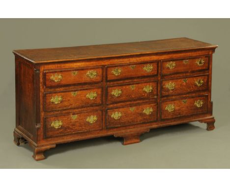 An 18th century oak and mahogany banded dresser base, with quartered and reeded columns, fitted with nine drawers and on ogee