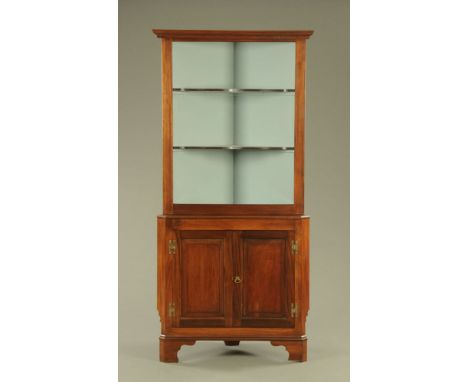 A George III mahogany double corner cupboard the upper stage with two shaped shelves above a double panelled door base with b