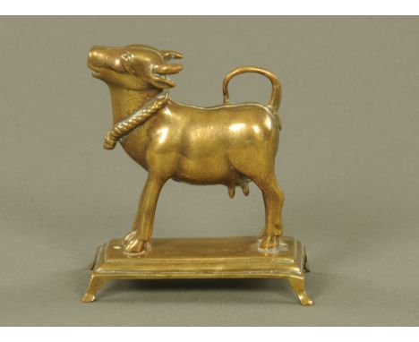 A 19th century Indian brass cow, with engraved decoration and raised on a rectangular plinth with bracket feet.  Height 14 cm