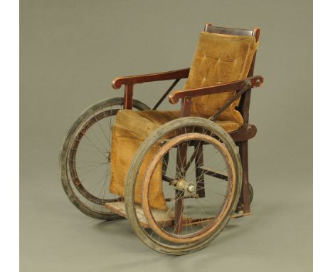 A vintage invalid chair, with bergere panelled back and loose cushions over with mahogany arms.  