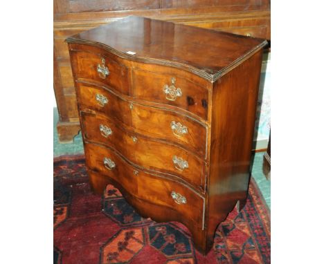 A mahogany reproduction serpentine fronted crossbanded chest of drawers, two short over three long with brass drop handles wi