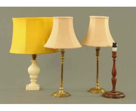 A pair of brass candlesticks, with plain cylindrical sconces and stems on circular bases, later fitted with plug in electric 