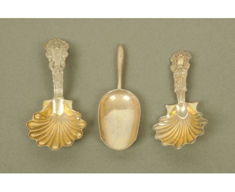 Two similar 19th century continental (possibly French) white metal caddy spoons, with scalloped gilded bowls, the terminals c
