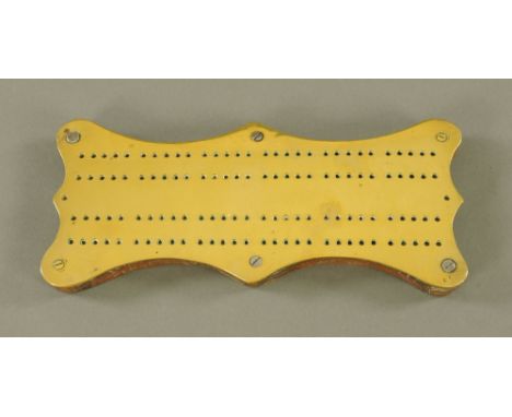 A Victorian brass and oak cribbage board, of shaped outline, 24 cm x 10 cm.