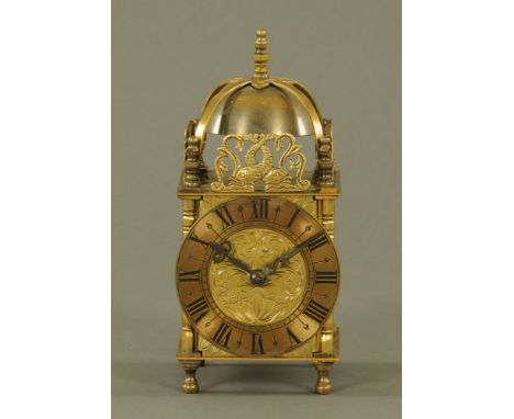 A miniature reproduction brass lantern clock, with spring driven movement.  Height 20 cm, width 9 cm.