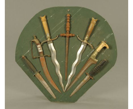 A dagger display, comprising 7 daggers of different types including Commando.  Largest 42 cm long, smallest 28 cm long, all m