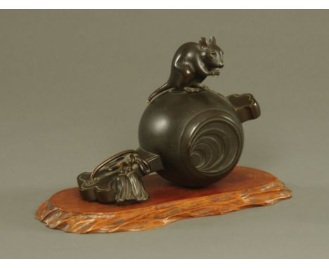 A 19th century Japanese bronze, depicting a rodent on top of a mallet, signed.  Height excluding wooden plinth 20 cm, length 