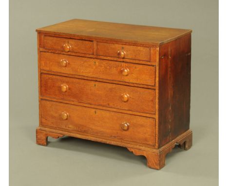 A George III oak chest of drawers, fitted with two short and three long drawers with later turned handles, on bracket feet.  