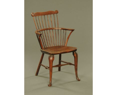 An 18th century ash and elm comb back two tier Windsor armchair, with shaped crest rail, curved arms, solid seat on cabriole 