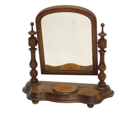 A Victorian oak dressing table mirror, with arched plate, on turned supports, a shaped base, with hinged trinket compartment,