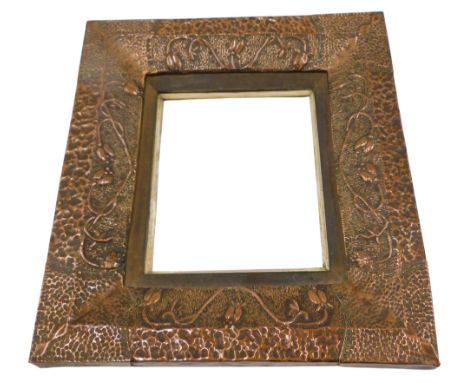 A late 19th/early 20thC embossed and hammered copper Arts &amp; Crafts frame, decorated with stylised flowers, etc., with riv