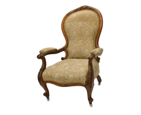 A Victorian walnut spoon back open armchair, with a padded back, arm rest and seat, on cabriole legs with castors.