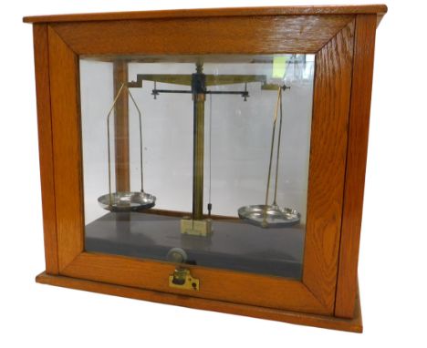 A set of brass chemist scales, in oak cabinet, 47cm wide.