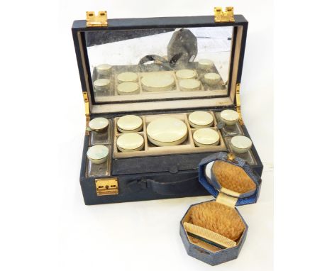 A blue leather dressing case with fitted interior, with glass bottles with enamel covers and an enamel brush and comb set in 