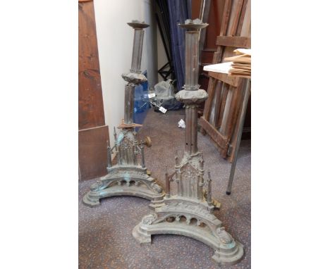 A large pair of ecclesiastical metal candlesticks in the Gothic revival style, each with triform bases surmounted by architec