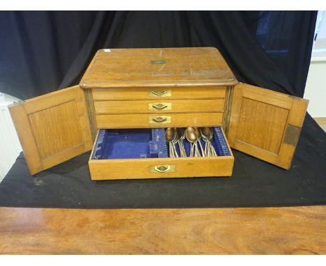 A LIGHT OAK CUTLERY CANTEEN with a brass lions crest to the top, 30cm high, partially populated with a bone-handled silver-pl