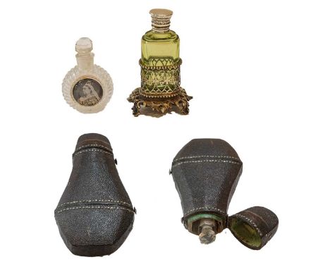 Three scent bottles, comprising: a clear glass example in double-hinged leather cased bottle, a green glass example in gilt-m