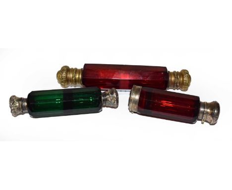 A Victorian faceted ruby glass double scent bottle with brass mounts, a similar emerald glass bottle with white metal tops an