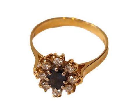 An 18 carat gold sapphire and diamond cluster ring, the oval cut sapphire, in white claw settings, within a border of round b