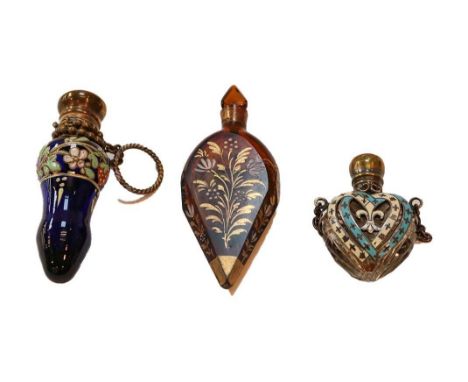 Three scent bottles, one heart-shaped, decorated with blue and white enamel; another of amber coloured glass with enamel deco