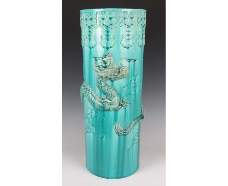 A Chinese turquoise glazed pottery stick stand, late Qing dynasty, of cylindrical form, modelled in high relief with a dragon