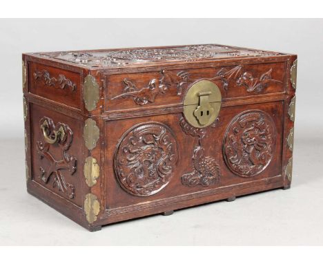 A Chinese brass mounted hardwood trunk, late Qing dynasty, the hinged lid carved in relief with a central dragon roundel surr