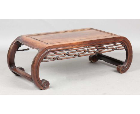 A Chinese hardwood low table, late 19th/early 20th century, the rectangular panelled top with curved ends and pierced scroll 