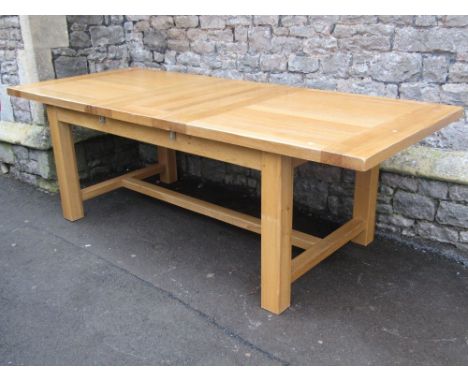 A good quality contemporary light oak pull out extending dining table of rectangular form with single additional leaf raised 