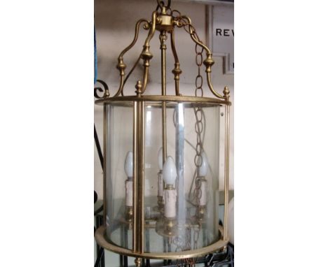 A large Georgian style hall/porch lantern of cylindrical form, the light brass frame enclosing glazed panels and four candle 