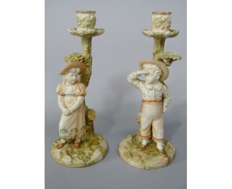 A pair of Victorian Royal Worcester candlesticks by James Hadley, both in the form of tree trunks with applied figures of chi