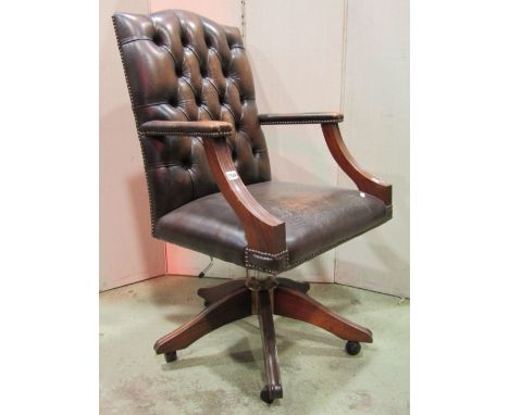 A reproduction swivel desk chair, with faux brown leather upholstered seat, button back and arms, with moulded frame, raised 