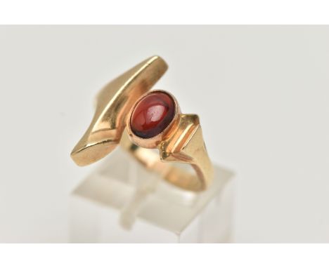 A 9CT GOLD GARNET DRESS RING, abstract design set with an oval garnet cabochon, collet set between abstract shoulders, leadin