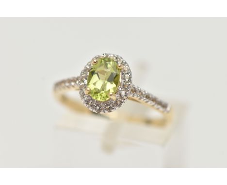A 9CT GOLD PERIDOT AND DIAMOND RING, an oval cut peridot, set with a surround of round brilliant cut diamonds, leading on to 