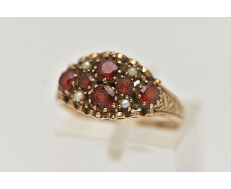 A 9CT GOLD GARNET AND SPLIT PEARL RING, set with six circular cut garnets and four split pearl accents, to the textured shoul