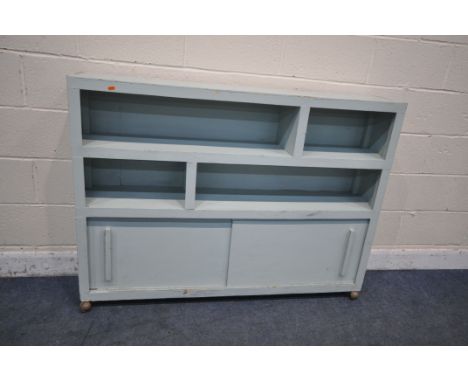 A 20TH CENTURY LIGHT BLUE PAINTED BOOKCASE, with two sliding doors, on later castors, width 138cm x depth 27cm x height 102cm