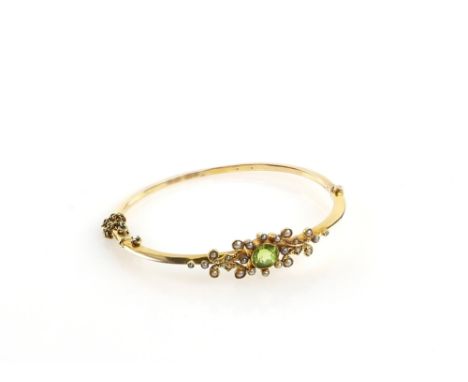 Edwardian oval hinged bangle, set with central round cut peridot and seed pearl, concealed clasp with safety chain, stamped 1