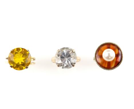 Three gem set rings; one round cut colourless topaz, ring size M, another set with a yellow paste stone, size L, both mounts 