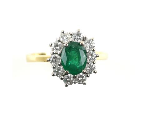 Emerald and diamond cluster ring, central oval cut emerald, estimated weight 1.16 carats, set within a frame of round brillia